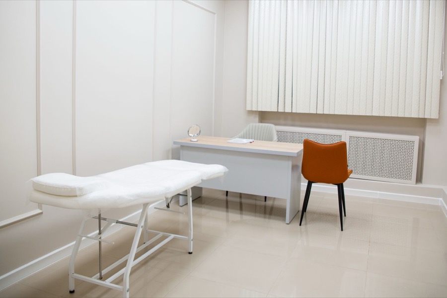 Cabinet de soin : table au drap blanc dans une pièce claire (photo d’illustration)